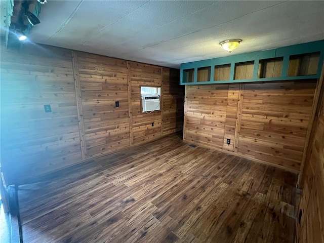 spare room with dark wood-style flooring, wood walls, and a wall mounted air conditioner