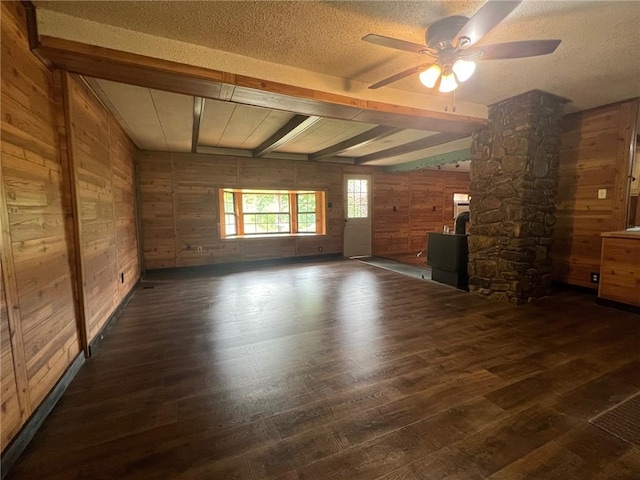 interior space with hardwood / wood-style flooring, a textured ceiling, ceiling fan, wooden walls, and beamed ceiling