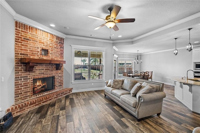 252 Forza Ln, Tontitown, AR 72762 - living area with baseboards, ornamental molding, ceiling fan with notable chandelier, dark wood-type flooring, and a fireplace