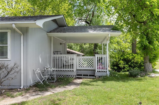 exterior space with roof with shingles and a lawn