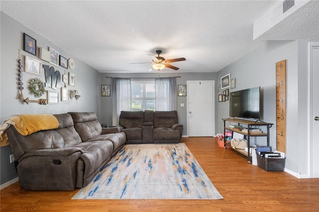 living room with a ceiling fan, baseboards, a textured ceiling, and wood finished floors