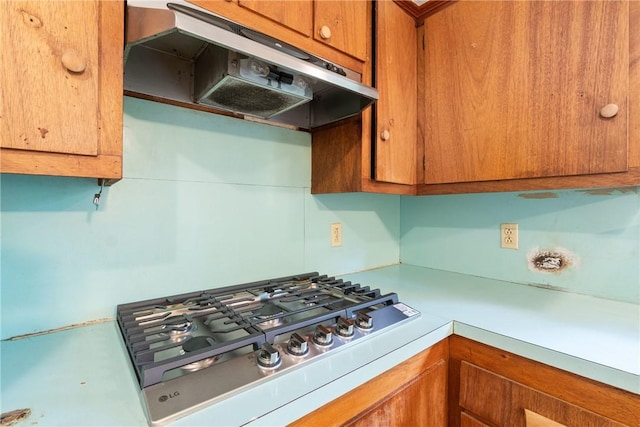 5 College St, Eureka Springs, AR 72632 - kitchen with under cabinet range hood, stainless steel gas cooktop, light countertops, and brown cabinets