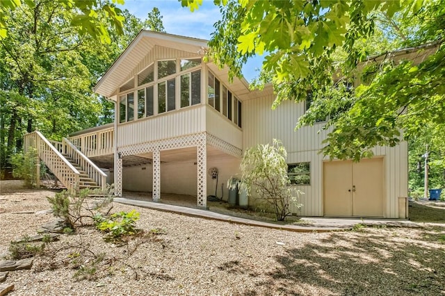 4 Tisbury Ln, Bella Vista, AR 72715 - rear view of property with a sunroom, a garage, stairs, and driveway