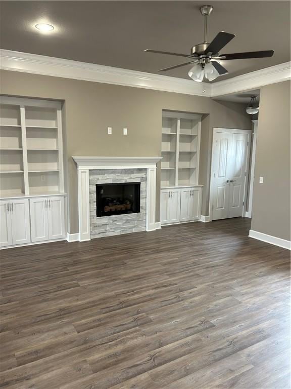 unfurnished living room with ornamental molding, built in shelves, a ceiling fan, baseboards, and wood finished floors