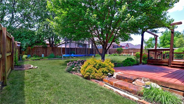 view of yard with a fenced backyard, a wooden deck, and a trampoline
