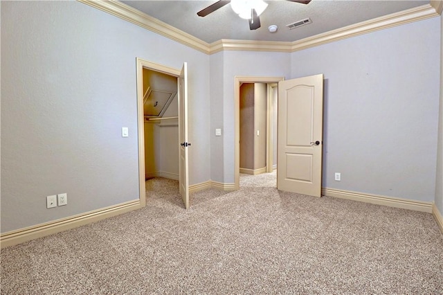 unfurnished bedroom with baseboards, ornamental molding, visible vents, a spacious closet, and carpet floors