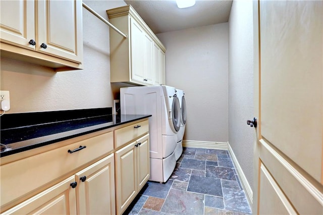 laundry room featuring baseboards, washing machine and dryer, stone tile floors, and cabinet space