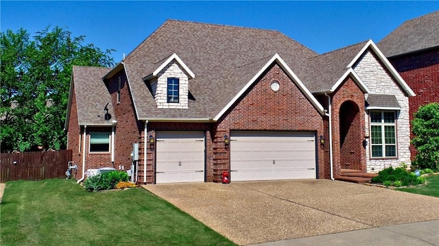 traditional-style home with fence, roof with shingles, a front yard, brick siding, and driveway