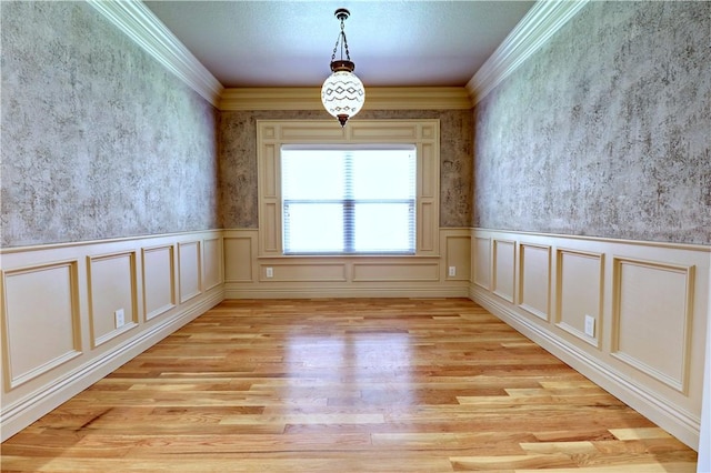 unfurnished room featuring crown molding, light wood-style flooring, and wainscoting