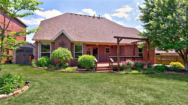 back of property with fence, a lawn, a wooden deck, a shed, and brick siding