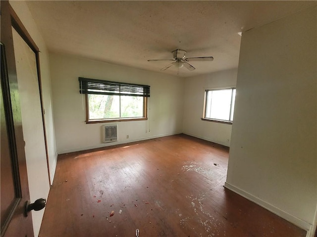 spare room with heating unit, wood finished floors, and baseboards