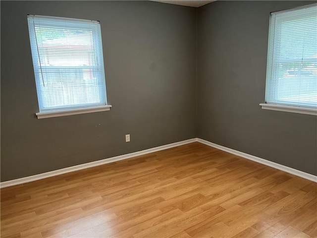 unfurnished room featuring light wood finished floors, plenty of natural light, and baseboards
