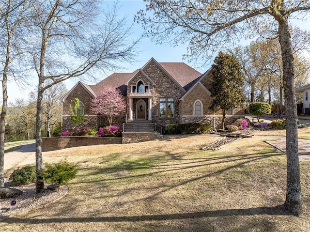 tudor-style house featuring stone siding, brick siding, and a front lawn
