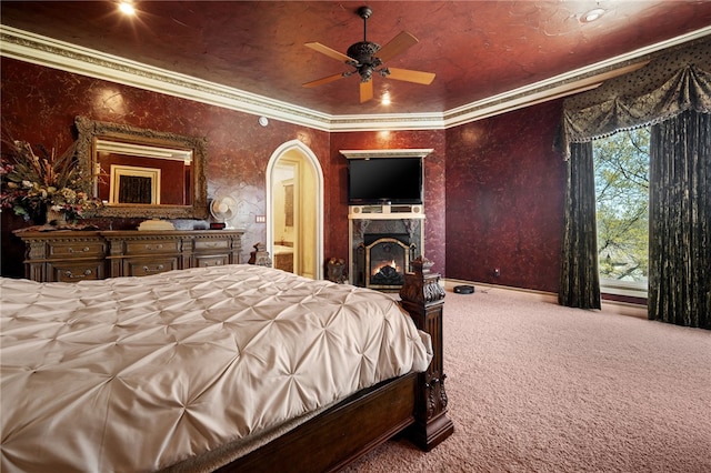 bedroom featuring a warm lit fireplace, ornamental molding, carpet flooring, and arched walkways