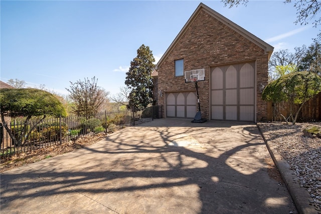 view of property exterior with fence, a garage, brick siding, and concrete driveway
