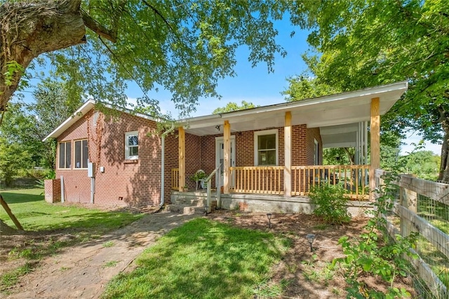 101 Carter Ln, Elkins, AR 72727 - ranch-style home featuring a porch, brick siding, a front lawn, and fence