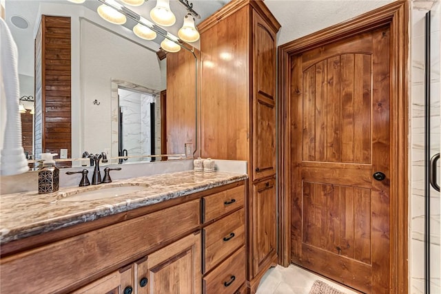 full bath featuring a shower with door, vanity, and tile patterned flooring
