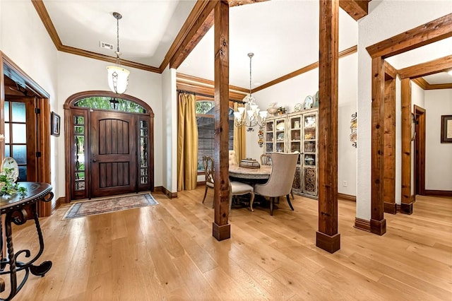 foyer entrance featuring baseboards, a notable chandelier, light wood-style flooring, and crown molding