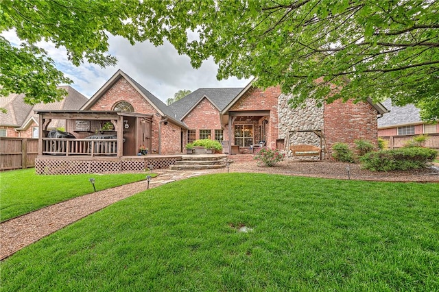view of front of property featuring covered porch, brick siding, a front lawn, and fence