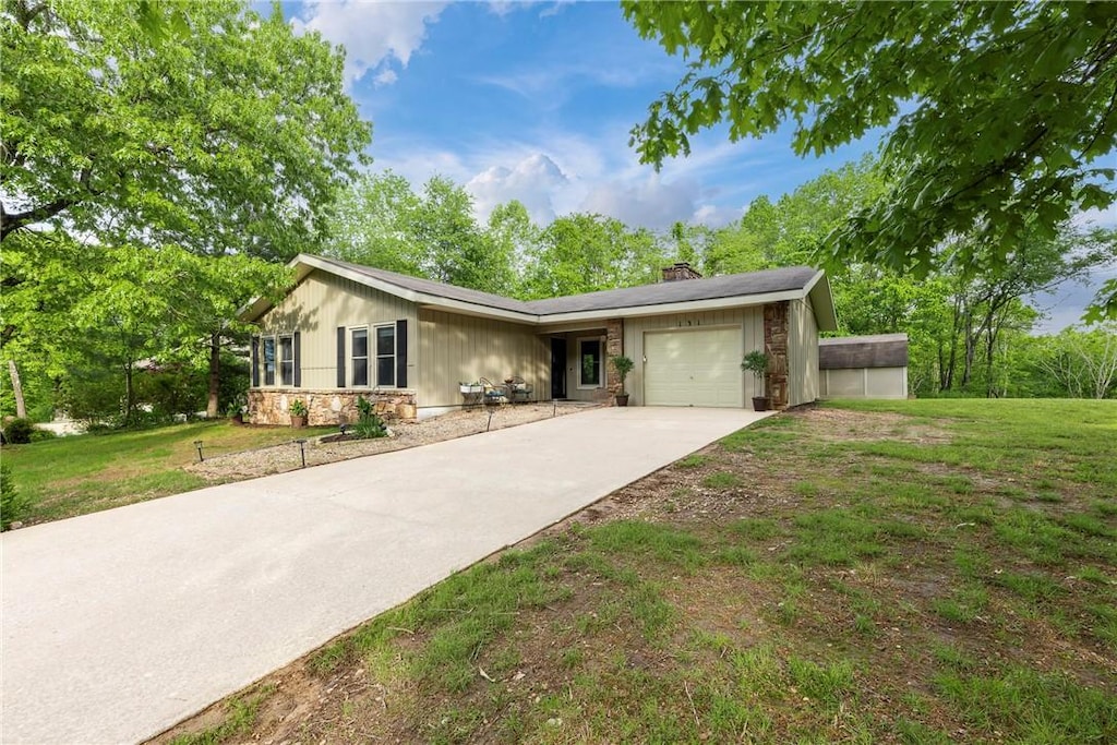 131 Kincardine Dr, Bella Vista, AR 72715 - ranch-style home with stone siding, a chimney, concrete driveway, a garage, and a front lawn