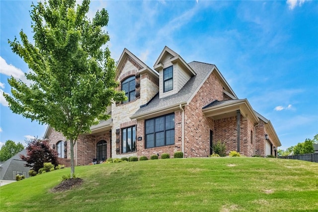 view of front of home with brick siding, a front lawn, and an attached garage