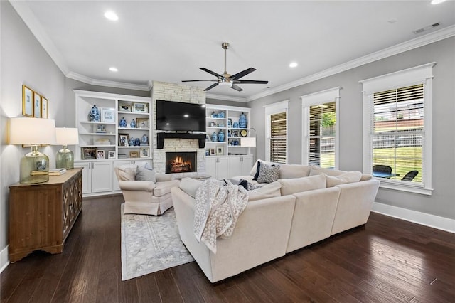 living room featuring a ceiling fan, crown molding, a fireplace, baseboards, and dark wood finished floors