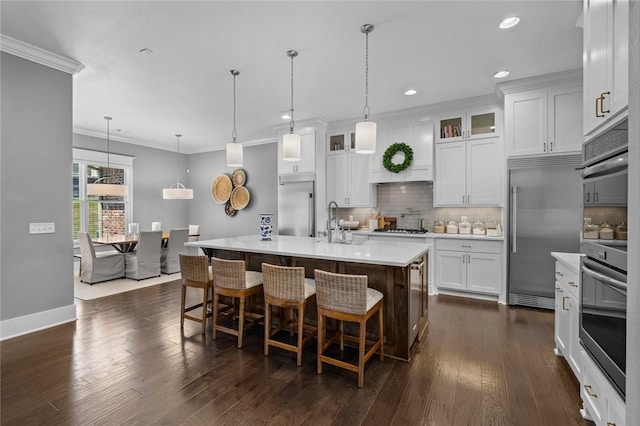 kitchen with stainless steel appliances, light countertops, backsplash, glass insert cabinets, and dark wood-style floors