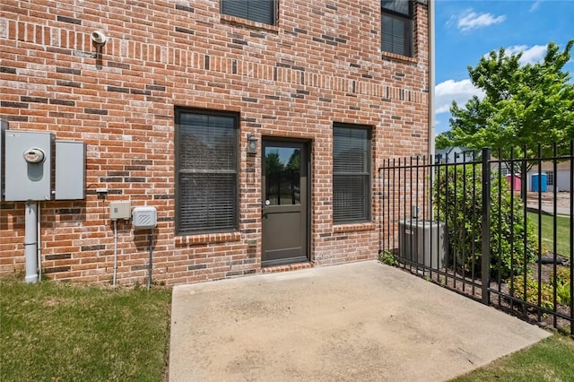 doorway to property with fence, brick siding, and a patio