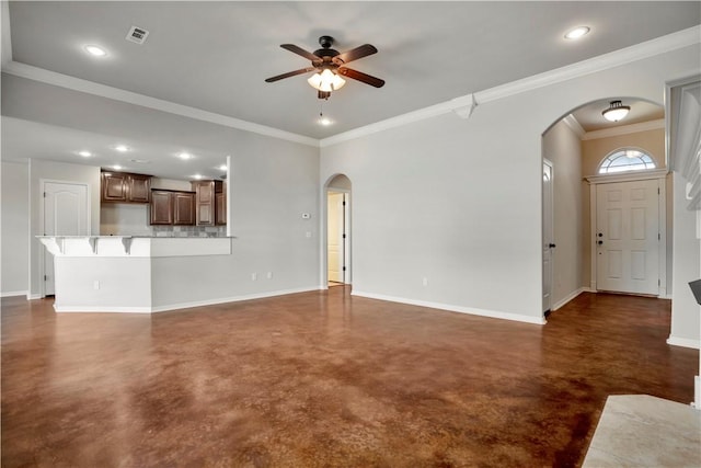 unfurnished living room featuring arched walkways, finished concrete flooring, ceiling fan, baseboards, and crown molding