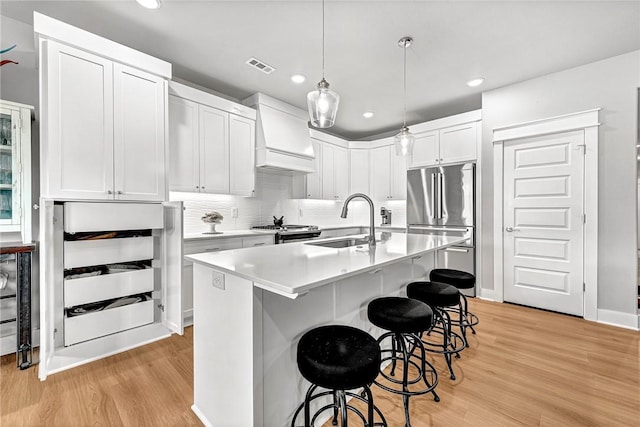 2227 Riggins Ave, Pea Ridge, AR 72751 - kitchen featuring a sink, premium range hood, a kitchen bar, light wood-style flooring, and white cabinets