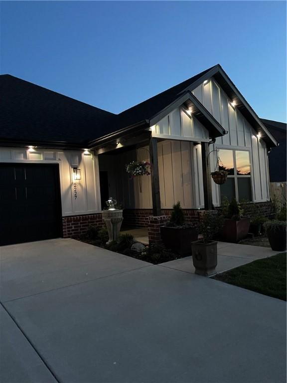 2227 Riggins Ave, Pea Ridge, AR 72751 - view of front of property featuring board and batten siding, brick siding, driveway, and an attached garage