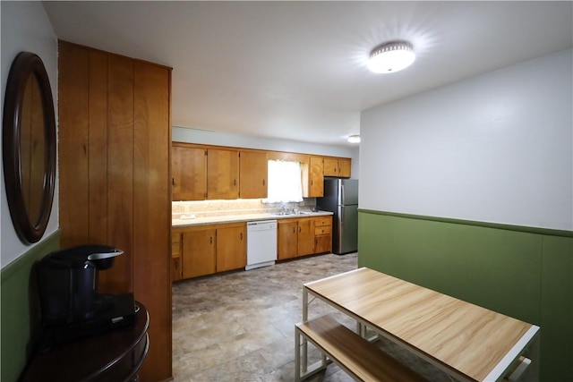 910 Sunset Ln, Harrison, AR 72601 - kitchen with white dishwasher, freestanding refrigerator, brown cabinets, light countertops, and a sink