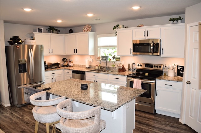 kitchen with stainless steel appliances, a sink, white cabinets, dark wood-style floors, and recessed lighting