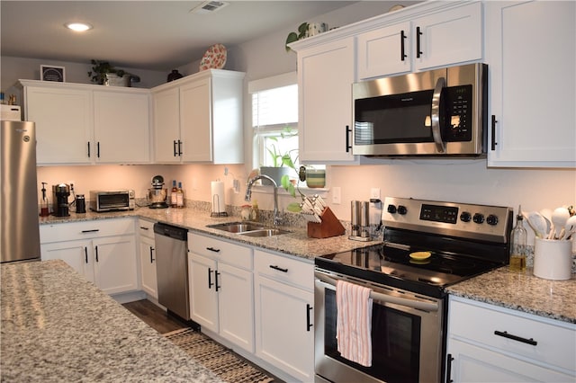 kitchen with stainless steel appliances, a sink, white cabinets, and recessed lighting
