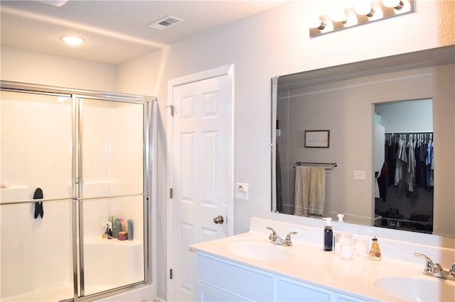 bathroom featuring a shower stall, double vanity, and recessed lighting