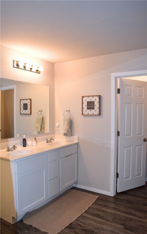 bathroom featuring wood finished floors, double vanity, and baseboards