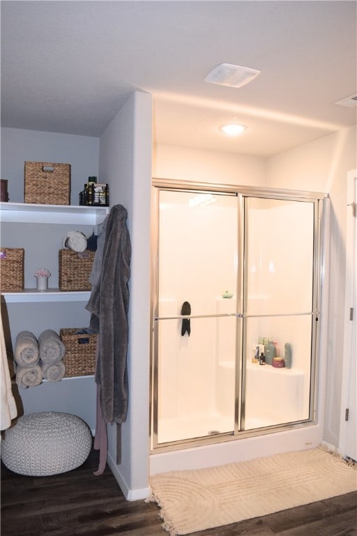 full bath featuring wood finished floors, a shower stall, and baseboards