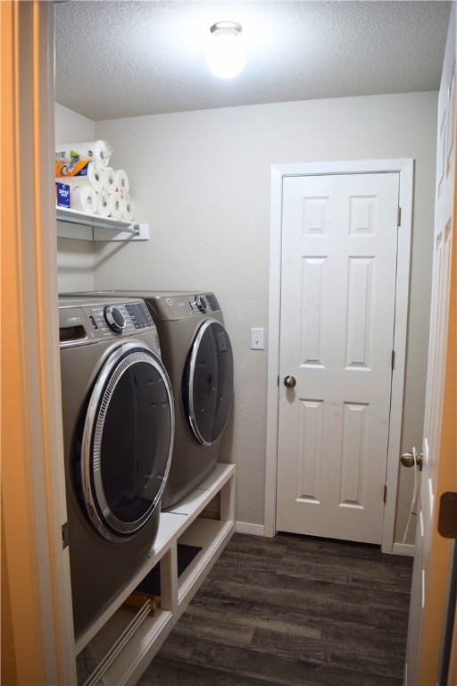 clothes washing area with washing machine and clothes dryer, dark wood-style flooring, a textured ceiling, and baseboards