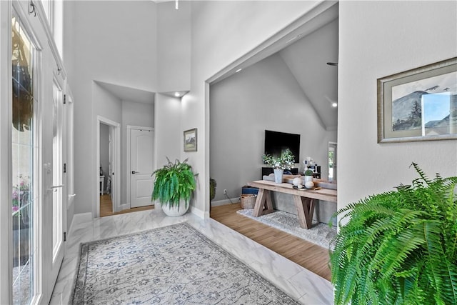 entrance foyer featuring a high ceiling, marble tiled flooring, and baseboards