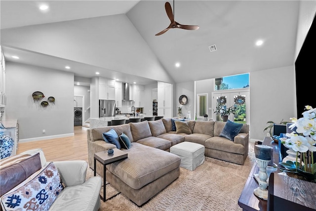 living room featuring washer / dryer, high vaulted ceiling, ceiling fan, recessed lighting, and light wood-type flooring