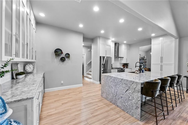 kitchen with stainless steel appliances, a sink, wall chimney range hood, recessed lighting, and baseboards