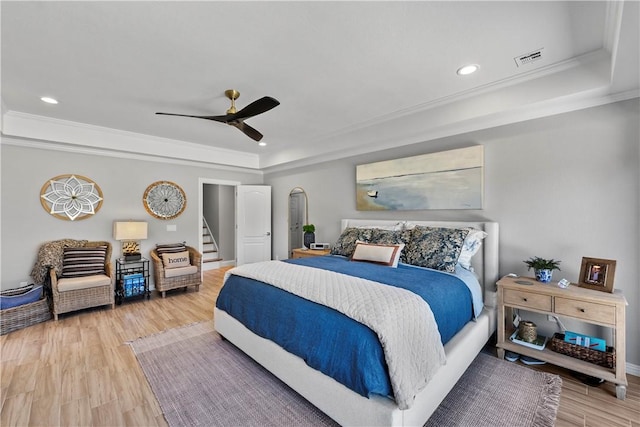 bedroom with a raised ceiling, light wood-style floors, recessed lighting, ornamental molding, and ceiling fan