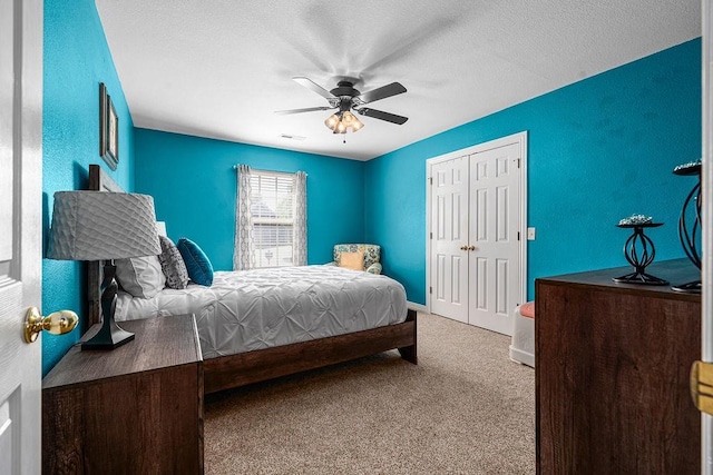 carpeted bedroom with a closet, a ceiling fan, baseboards, and a textured ceiling
