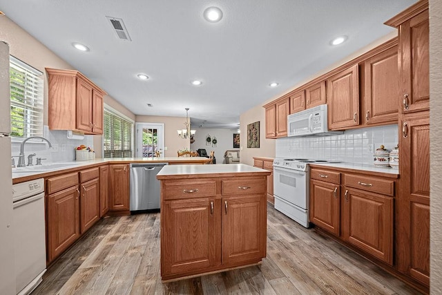 kitchen with white appliances, a sink, light countertops, decorative backsplash, and recessed lighting