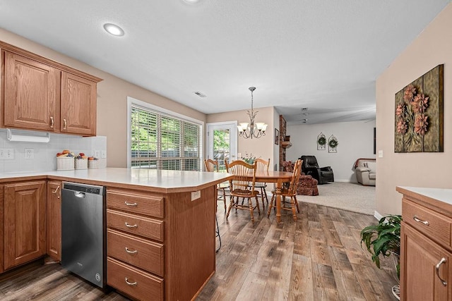 kitchen with dishwasher, a peninsula, light countertops, open floor plan, and a chandelier