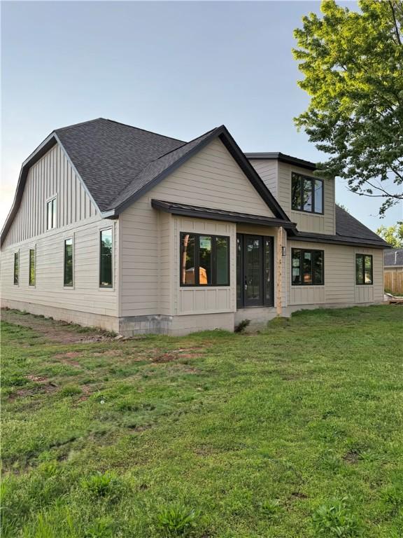 502 Concord St, Lowell, AR 72745 - rear view of property with a shingled roof, a lawn, and board and batten siding
