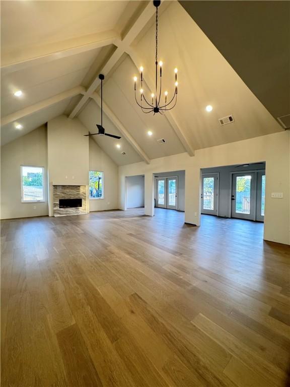 502 Concord St, Lowell, AR 72745 - unfurnished living room featuring wood finished floors, beam ceiling, a ceiling fan, a chandelier, and a fireplace