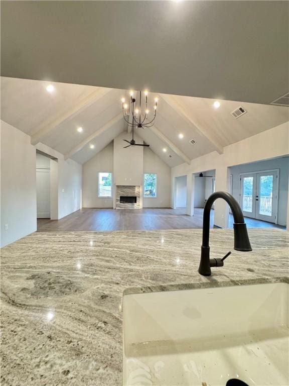 502 Concord St, Lowell, AR 72745 - unfurnished living room featuring a sink, healthy amount of natural light, beam ceiling, wood finished floors, and a chandelier