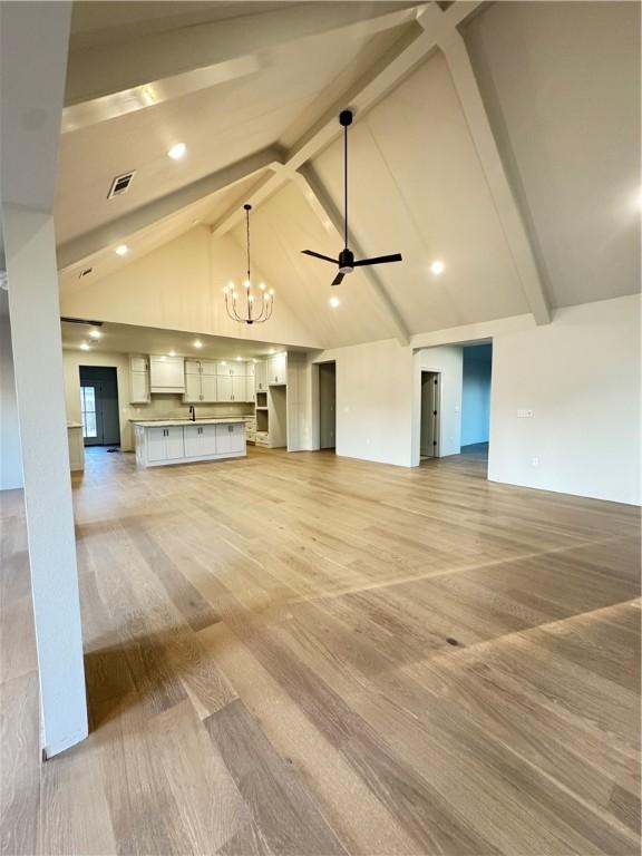 502 Concord St, Lowell, AR 72745 - unfurnished living room featuring beam ceiling, light wood-type flooring, a chandelier, a ceiling fan, and high vaulted ceiling