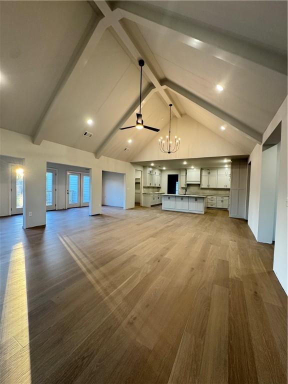 502 Concord St, Lowell, AR 72745 - unfurnished living room with wood finished floors, a chandelier, beamed ceiling, high vaulted ceiling, and a ceiling fan